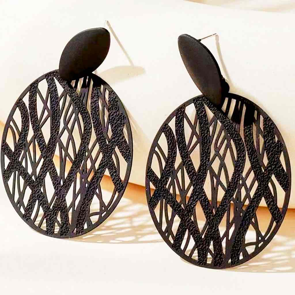 A pair of black abstract cutout boho earrings with a matte finish, featuring an oval stud and a large circular drop with intricate wavy patterns.