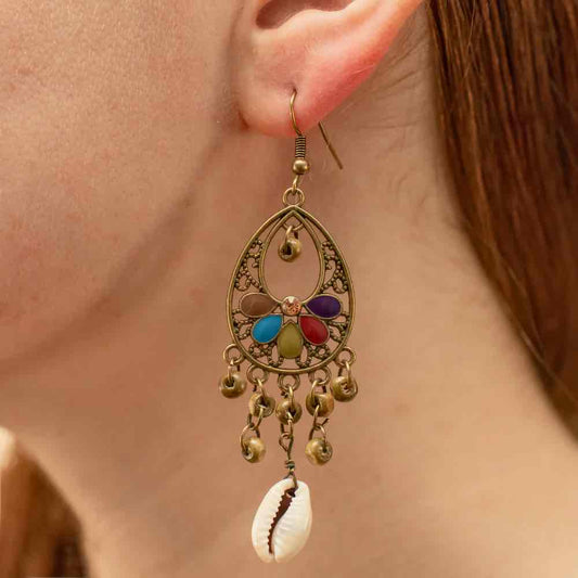 A woman wearing a single oxidised floral shell drop earring, showcasing its bohemian design and natural shell accent.