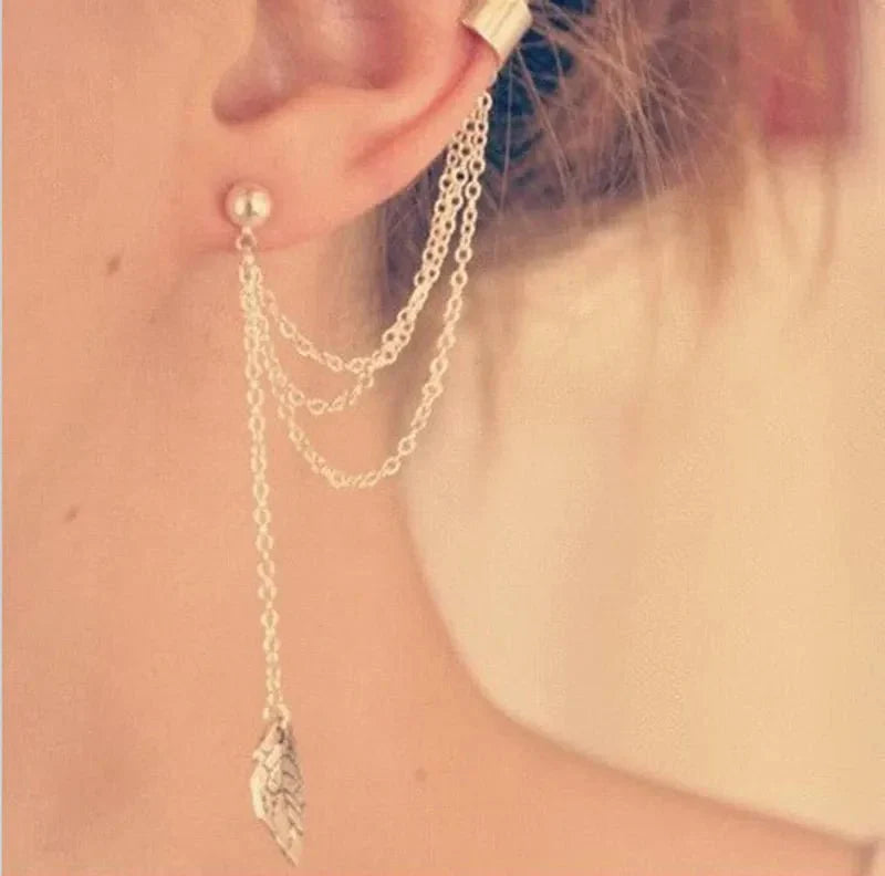Close-up of a silver chain drop earring with a stud and an ear cuff, featuring a leaf pendant, highlighting the long earrings design.