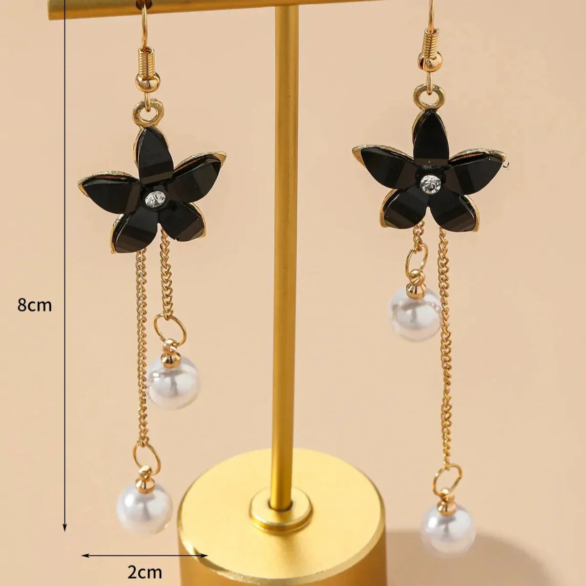 Pair of black floral long earrings with pearl chain dangle displayed on a gold stand, showing 8cm length and 2cm width.