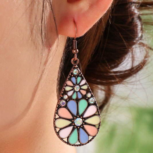 Close-up of a woman wearing a single bohemian floral teardrop earring with pastel enamel and small clear stones.