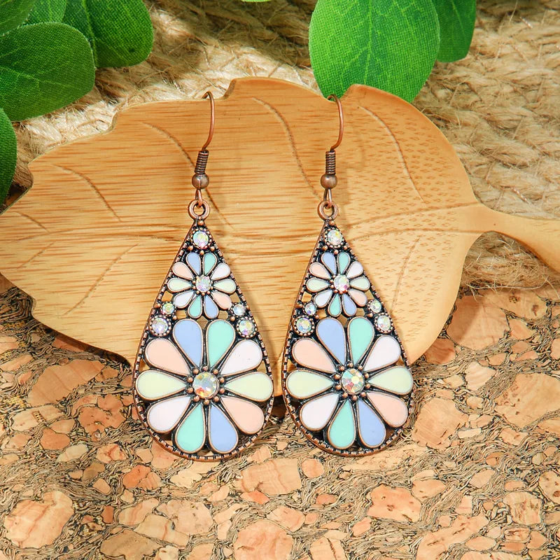 Pair of bohemian floral teardrop earrings with pastel enamel and small clear stones, displayed on a wooden leaf-shaped tray.