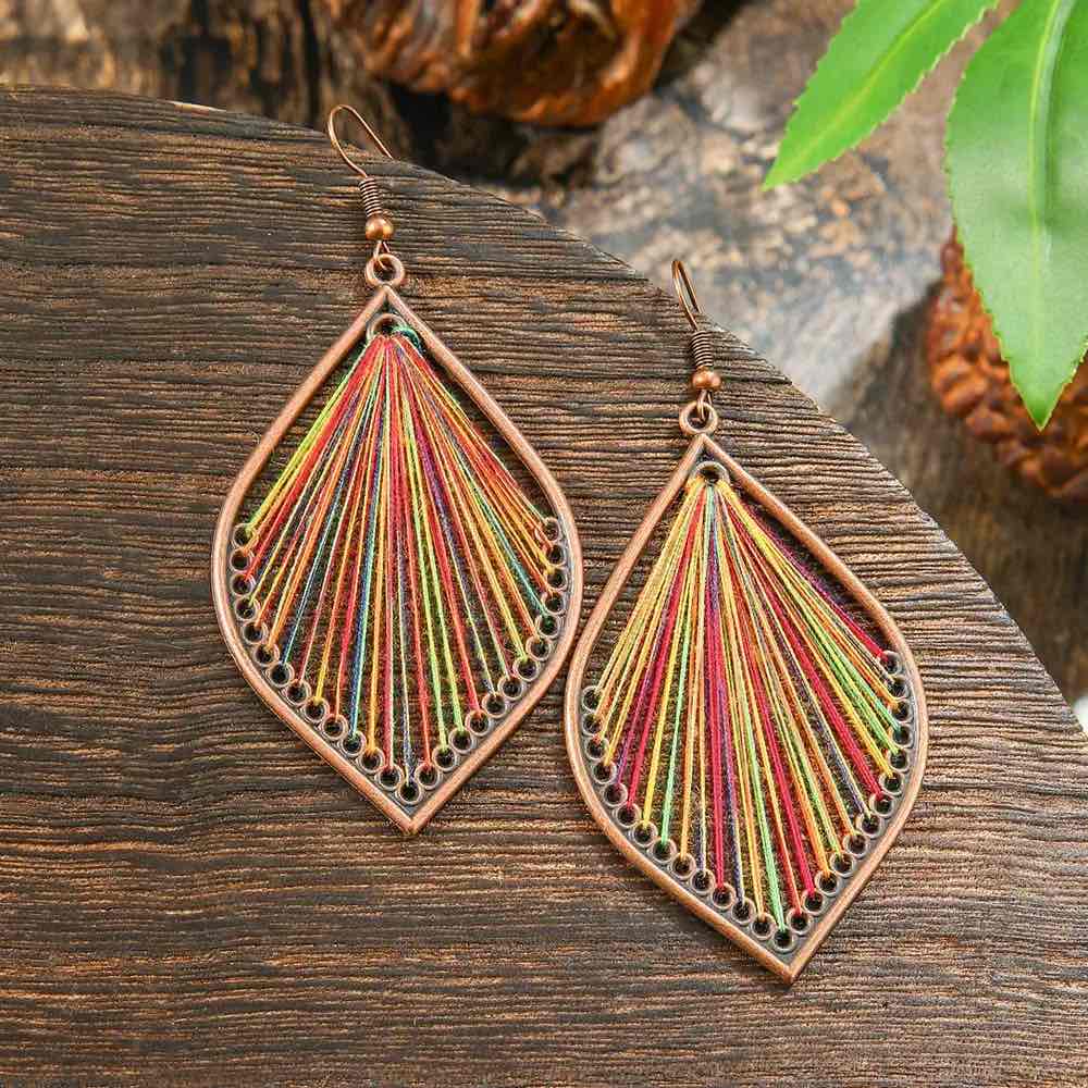 Close-up of a single bohemian earring with a bronze-toned teardrop frame and intricate multicolor thread work, highlighting the detailed craftsmanship of the boho earrings.