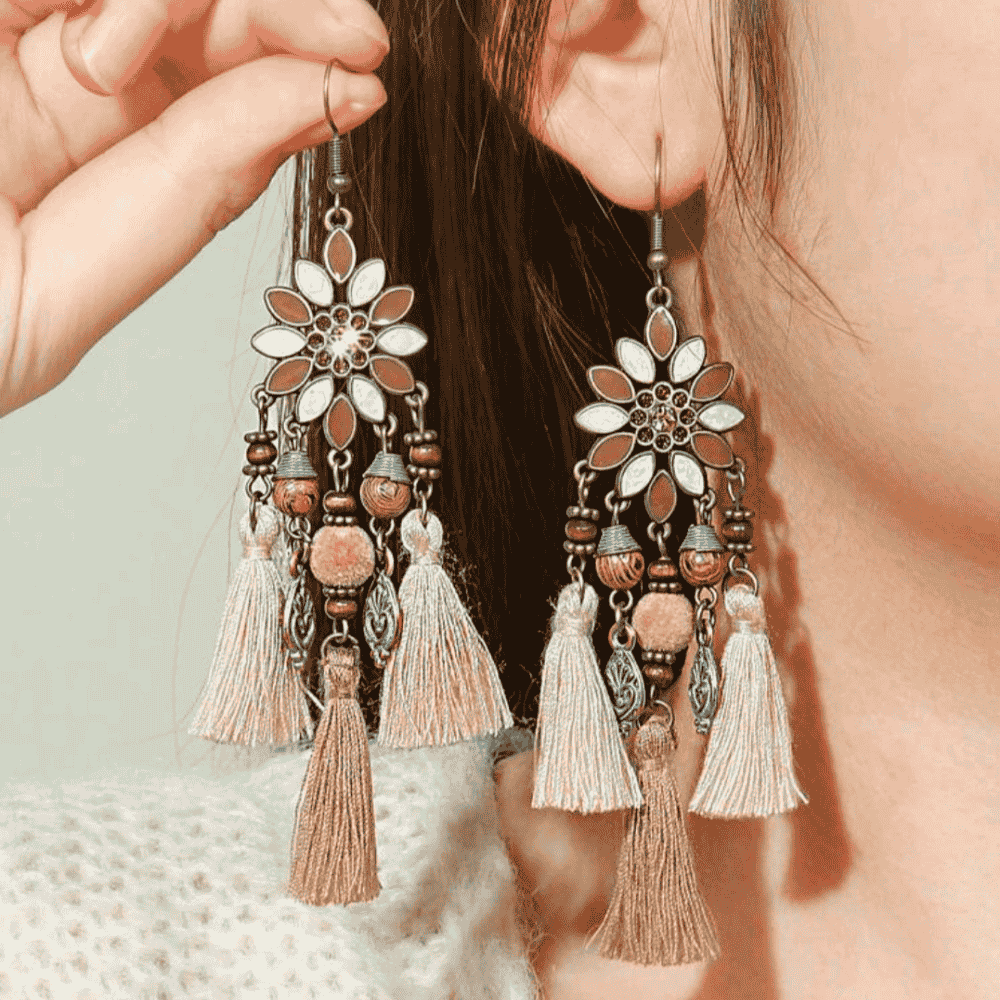 A person wearing one of the long boho earrings, showcasing its size and how it drapes, with a focus on the floral and tassel details.