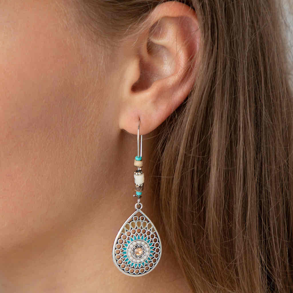 A woman wearing a single boho earring, showcasing the oxidised silver teardrop mandala design with turquoise and brown beads.