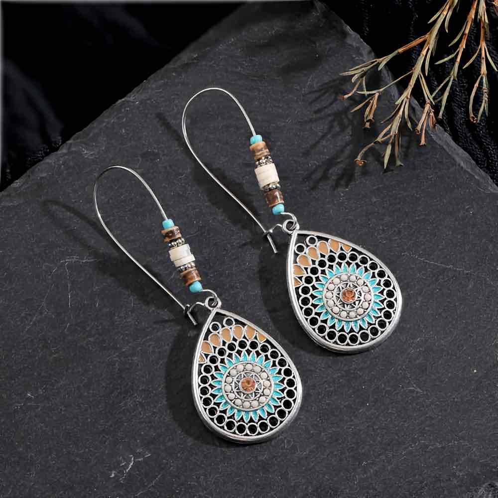 A woman wearing a single boho earring, showcasing the oxidised silver teardrop mandala design with turquoise and brown beads.