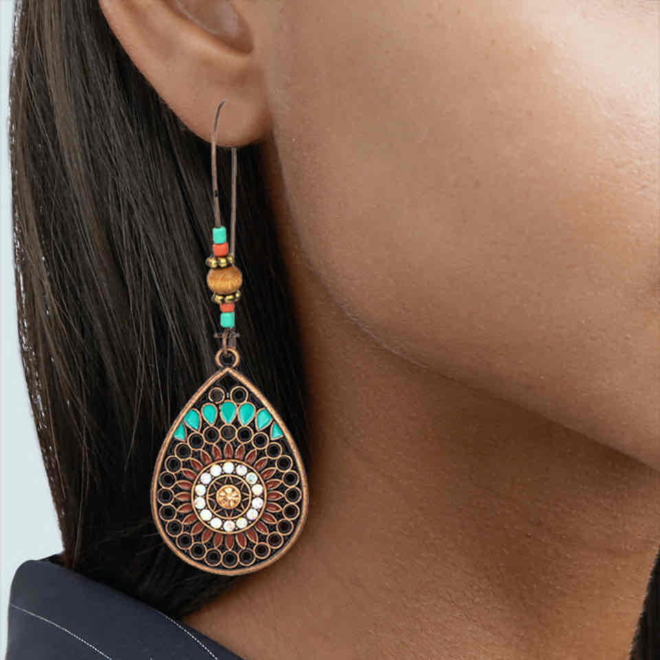 A model wearing a single boho earring, showcasing its length and intricate design with turquoise and beaded details against dark hair.