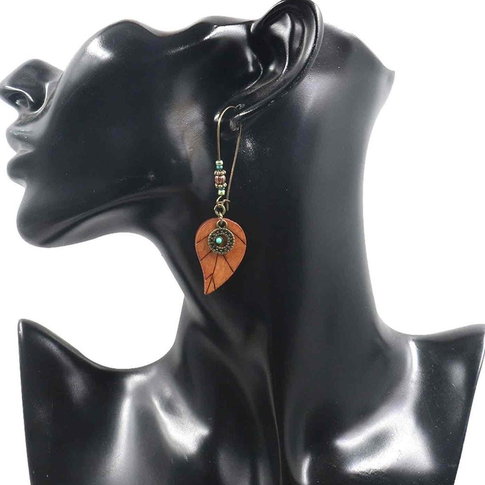A model wearing a single boho wooden leaf drop earring with turquoise accents, showcasing its length and style.