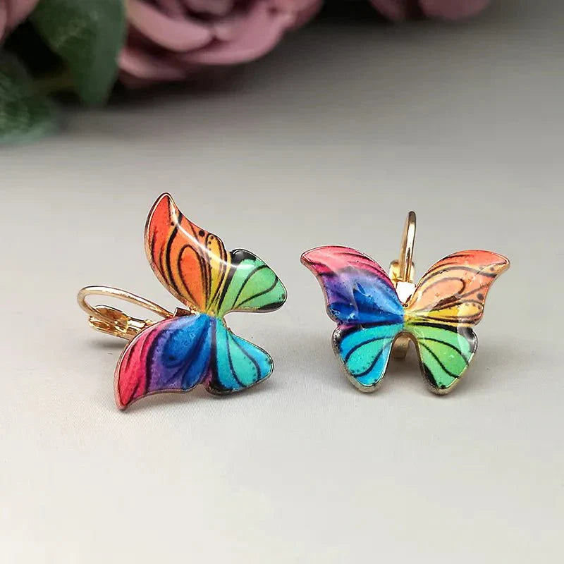 A pair of rainbow-colored enamel butterfly korean earrings with lever-back closures, set against a light background.