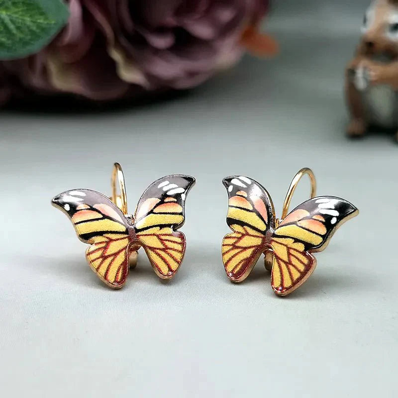 A pair of yellow and orange enamel butterfly korean earrings with black and white accents, featuring lever-back closures.