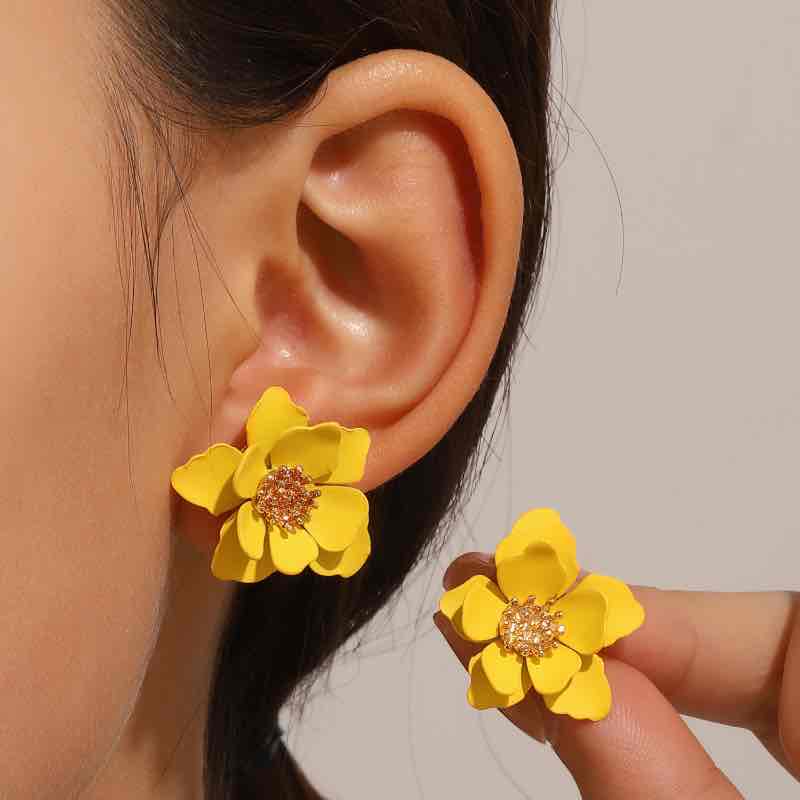A woman with brown hair wearing a navy blue Korean flower stud earring, looking to the side.