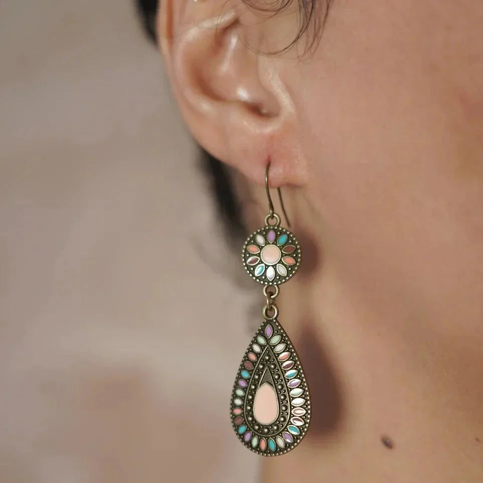 A close-up of a woman wearing a single oxidised earring with multi-color enamel floral and teardrop designs.