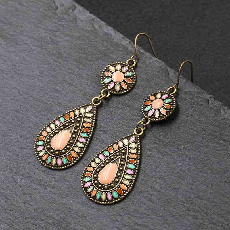 A pair of oxidised earrings with multi-color enamel floral and teardrop designs, displayed on a wooden surface.