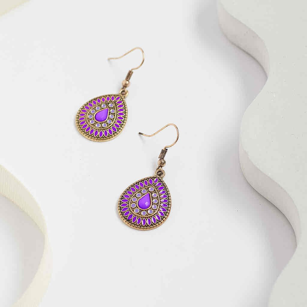 A pair of deep purple enamel teardrop drop earrings with an antique gold finish, arranged on a clean white background with subtle decorative elements.