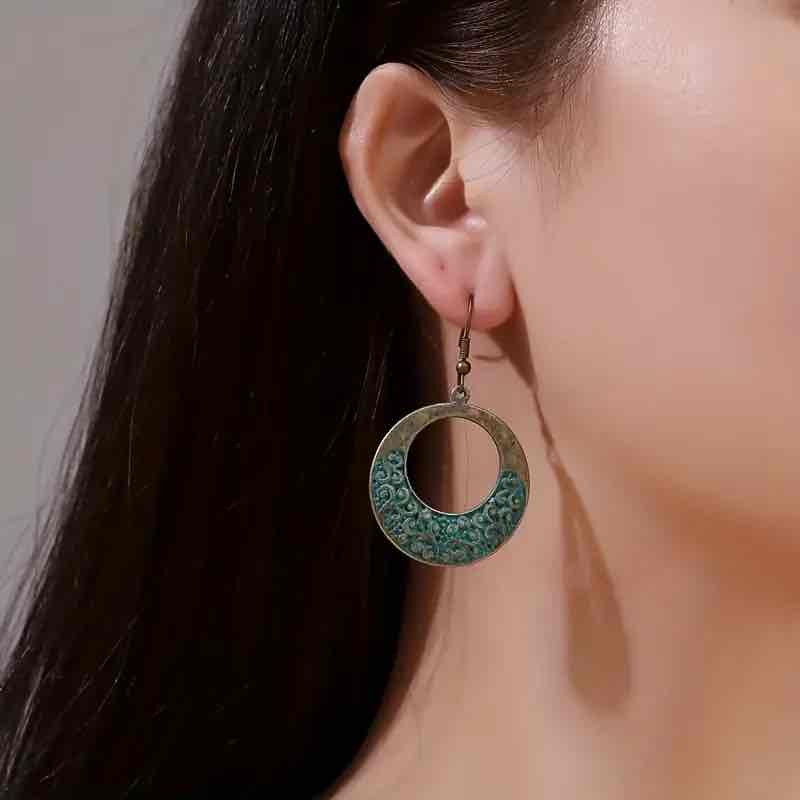 A woman wearing a single oxidised boho hoop earring, showcasing its size and how it hangs.