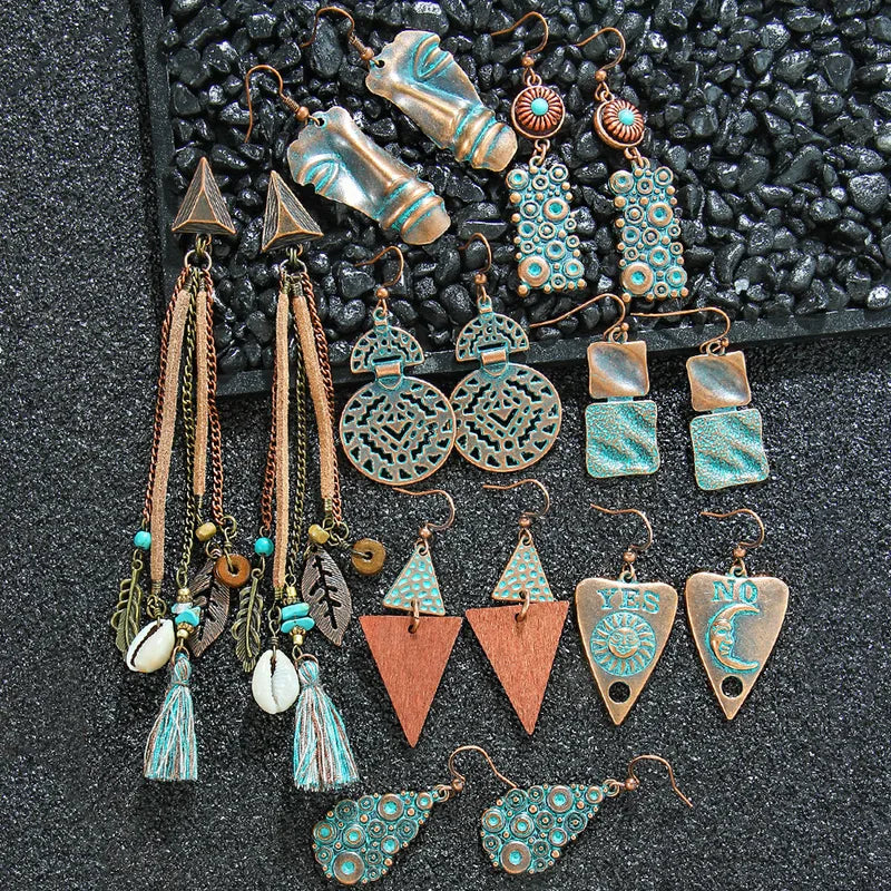 A collection of various oxidised earrings, including the geometric oxidised earrings, displayed on a dark textured surface.