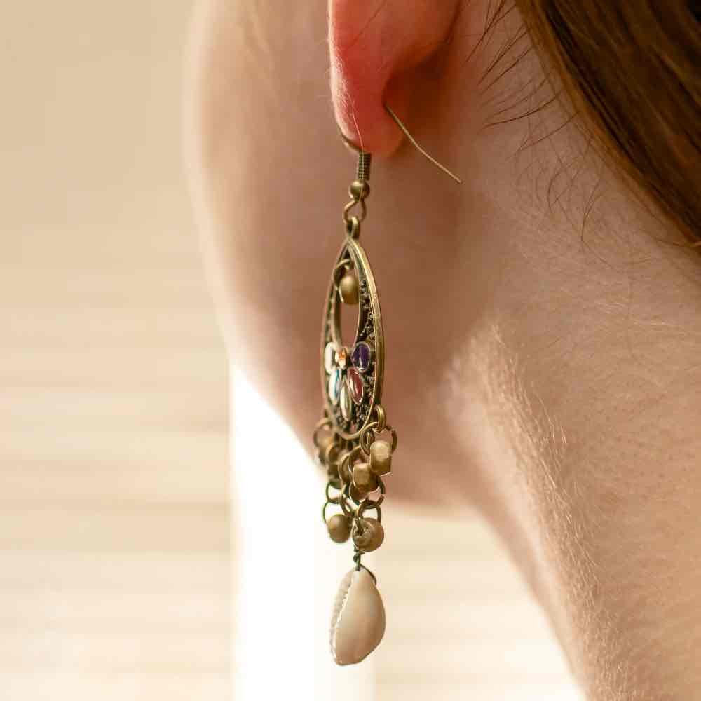 Close-up of a single oxidised floral shell drop earring with blue and black enamel, highlighting the intricate filigree work.