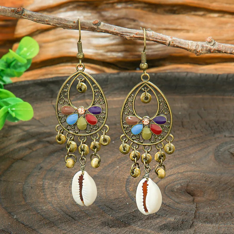 A woman wearing a single oxidised floral shell drop earring, showing its length and how it complements her ear.