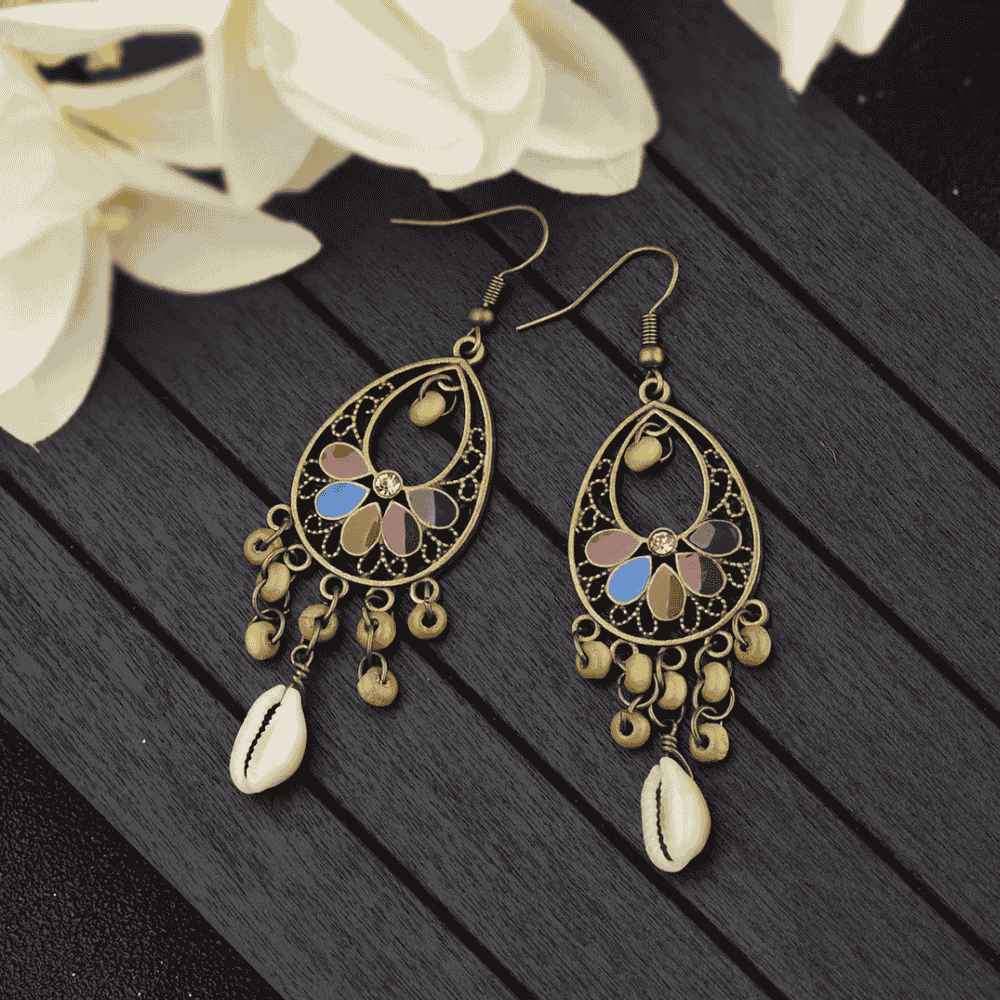 A pair of oxidised floral shell drop earrings with colorful enamel details, displayed against a dark background.