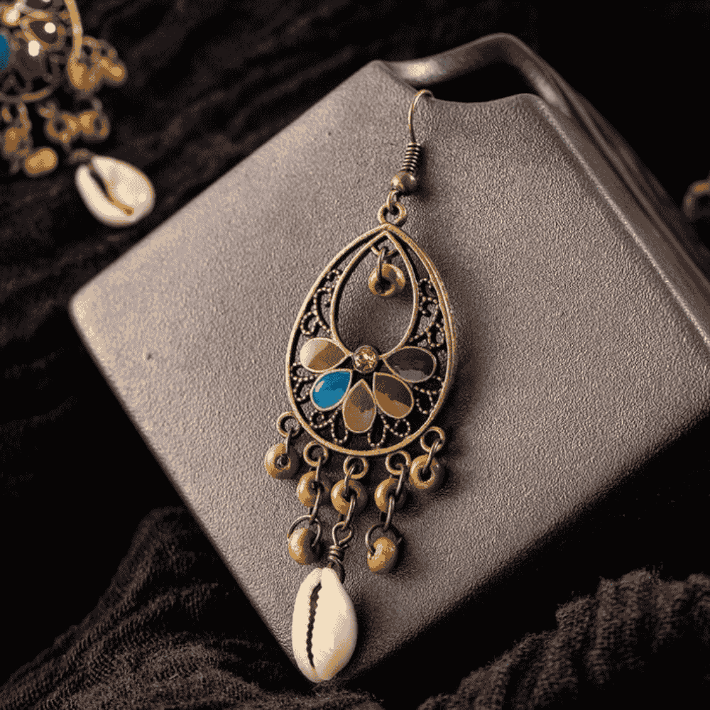 Close-up of a single oxidised floral shell drop earring, focusing on the cowrie shell and small bead accents.