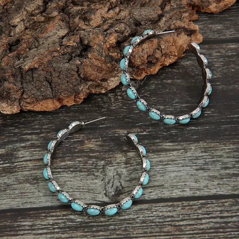 Detailed view of the mid-section of an oxidised silver hoop earring, highlighting the oval turquoise stones and the start of 