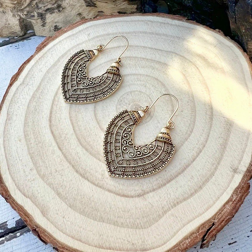 Unique oxidised crescent drop earrings with intricate scrollwork design, displayed on a wooden surface - front view | Earthy Origin