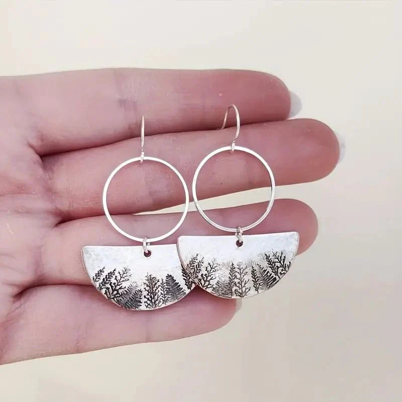 A pair of oxidised earrings with a half-moon forest fern design, showing the back of the earrings.
