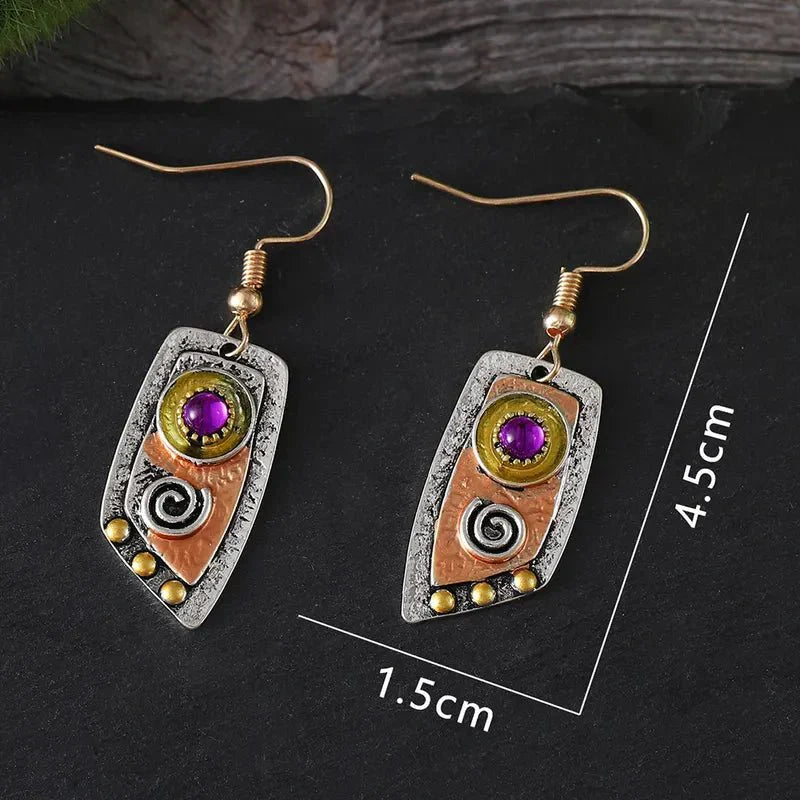 A pair of oxidised earrings with purple stones and tribal spiral designs, with dimensions 4.5cm length and 1.5cm width.