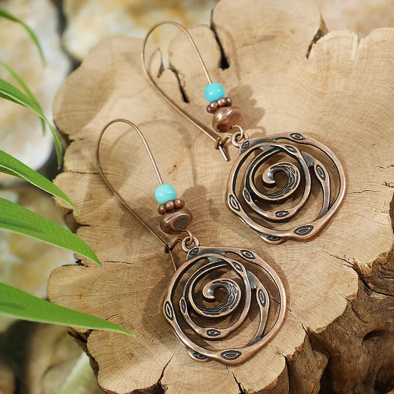 Unique oxidised dangle earrings with spiral design and blue beads - Front view | Earthy Origin
