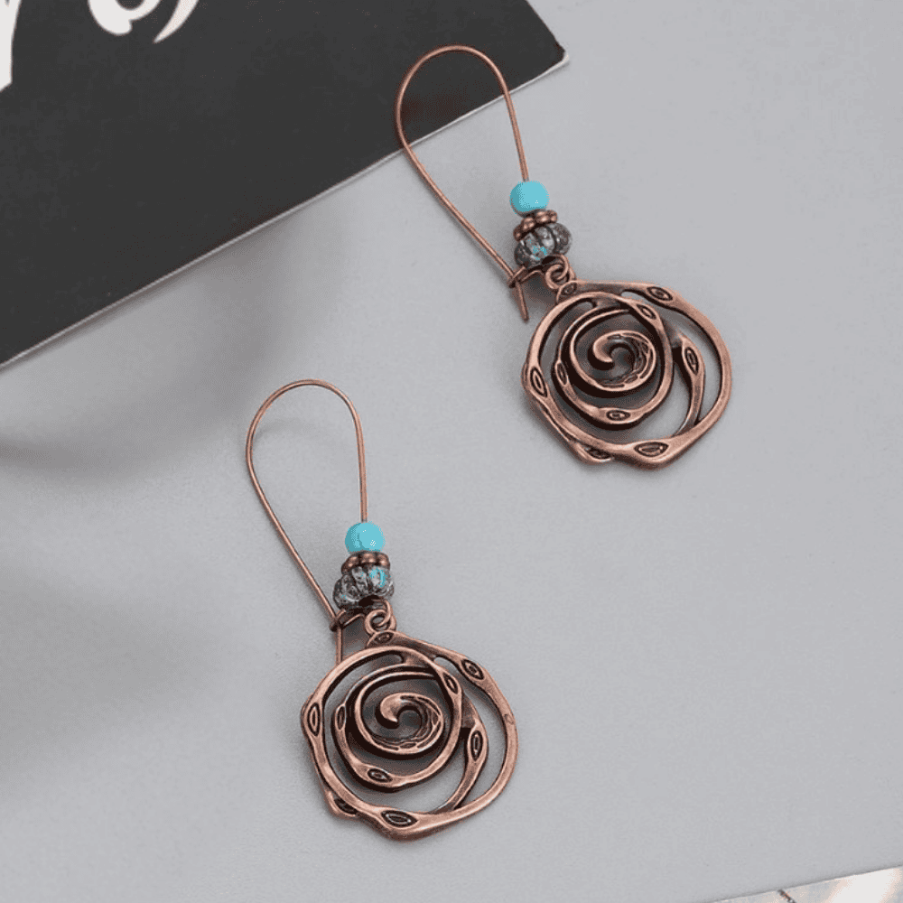 Close-up of unique oxidised earrings featuring spiral motif and turquoise beads | Earthy Origin