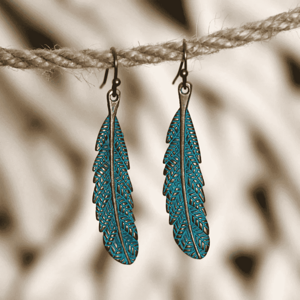 Close-up of a single unique oxidised feather earring showing intricate texture and teal finish | Earthy Origin