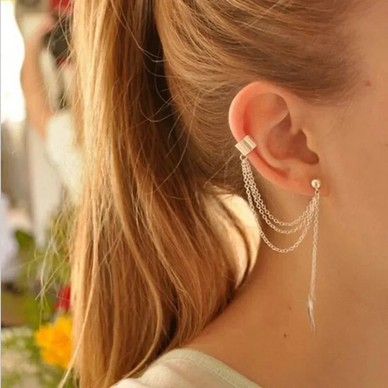 A woman wearing a silver chain drop earring with an ear cuff and a leaf charm, showcasing the long earrings style.