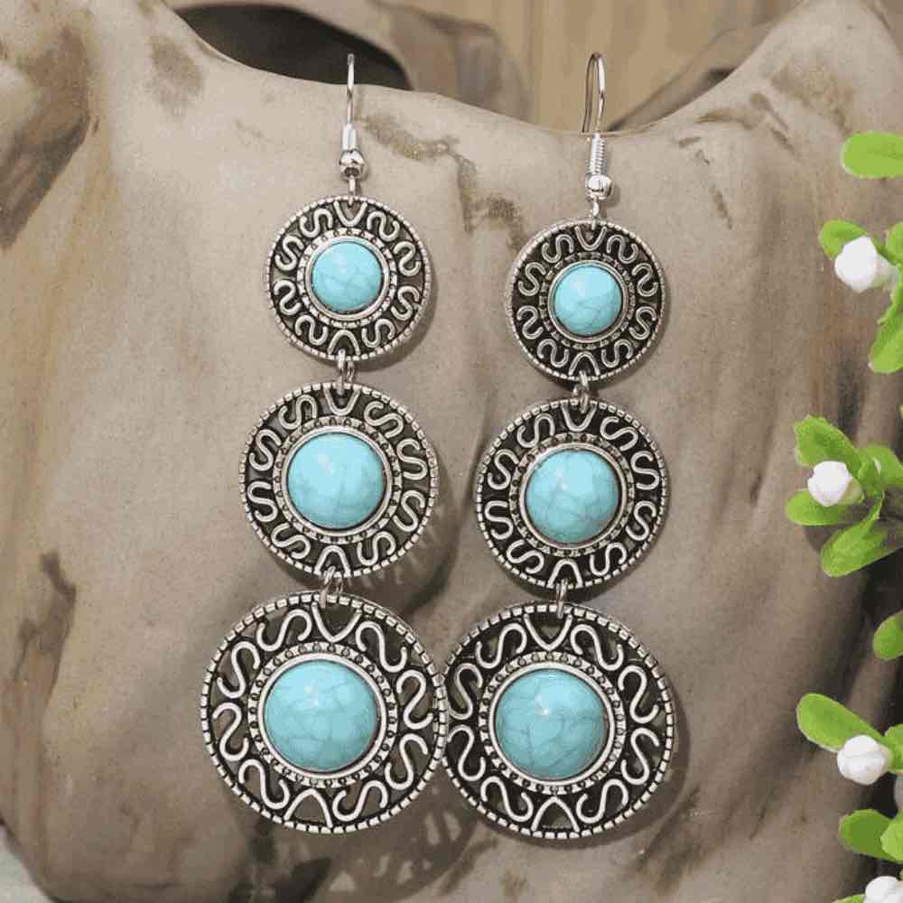 Detailed view of the top two circular segments of the right turquoise earring, showing the fishhook and scroll patterns.